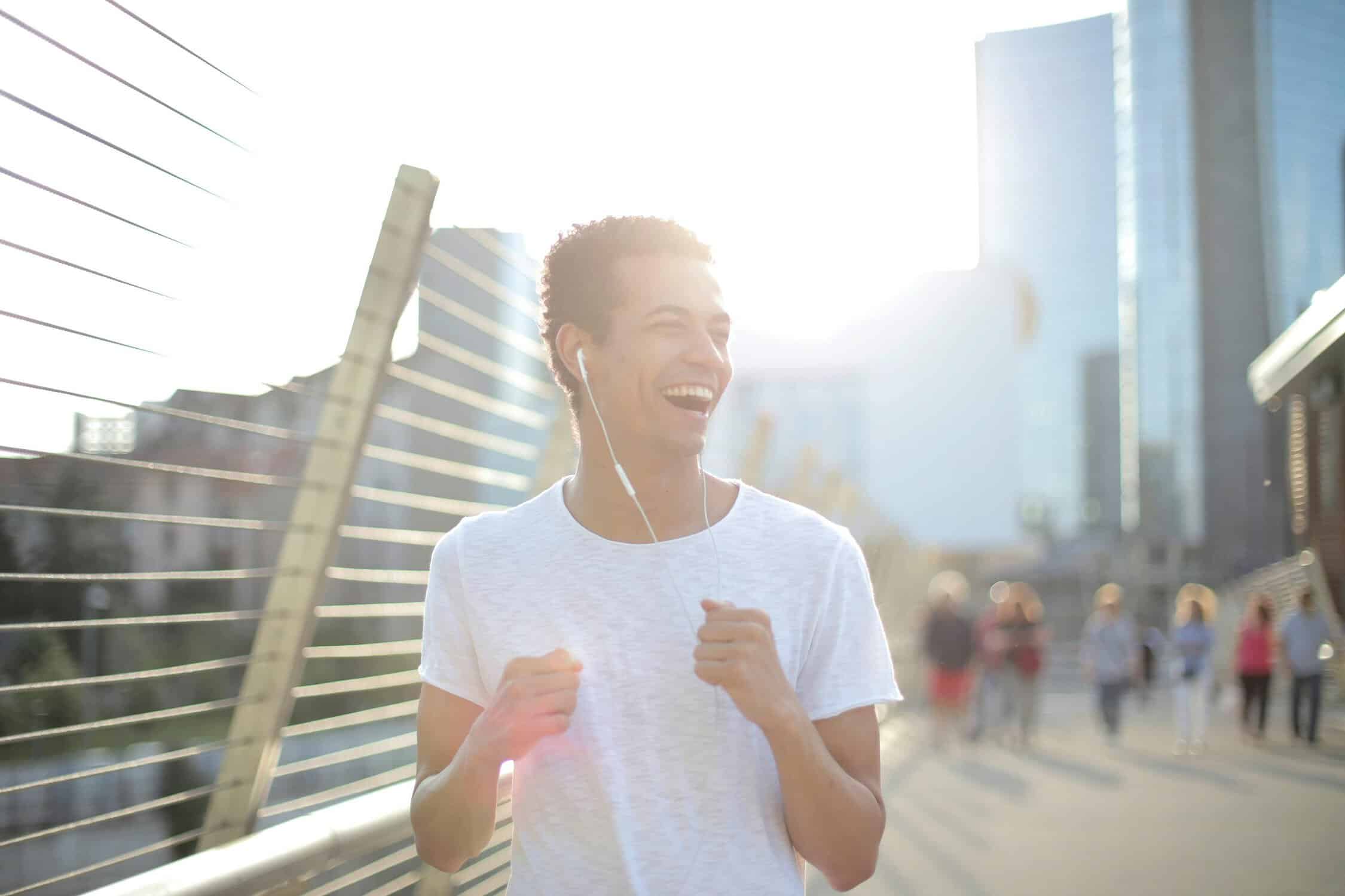 A man running through a city with headphones, listening to the best running songs.