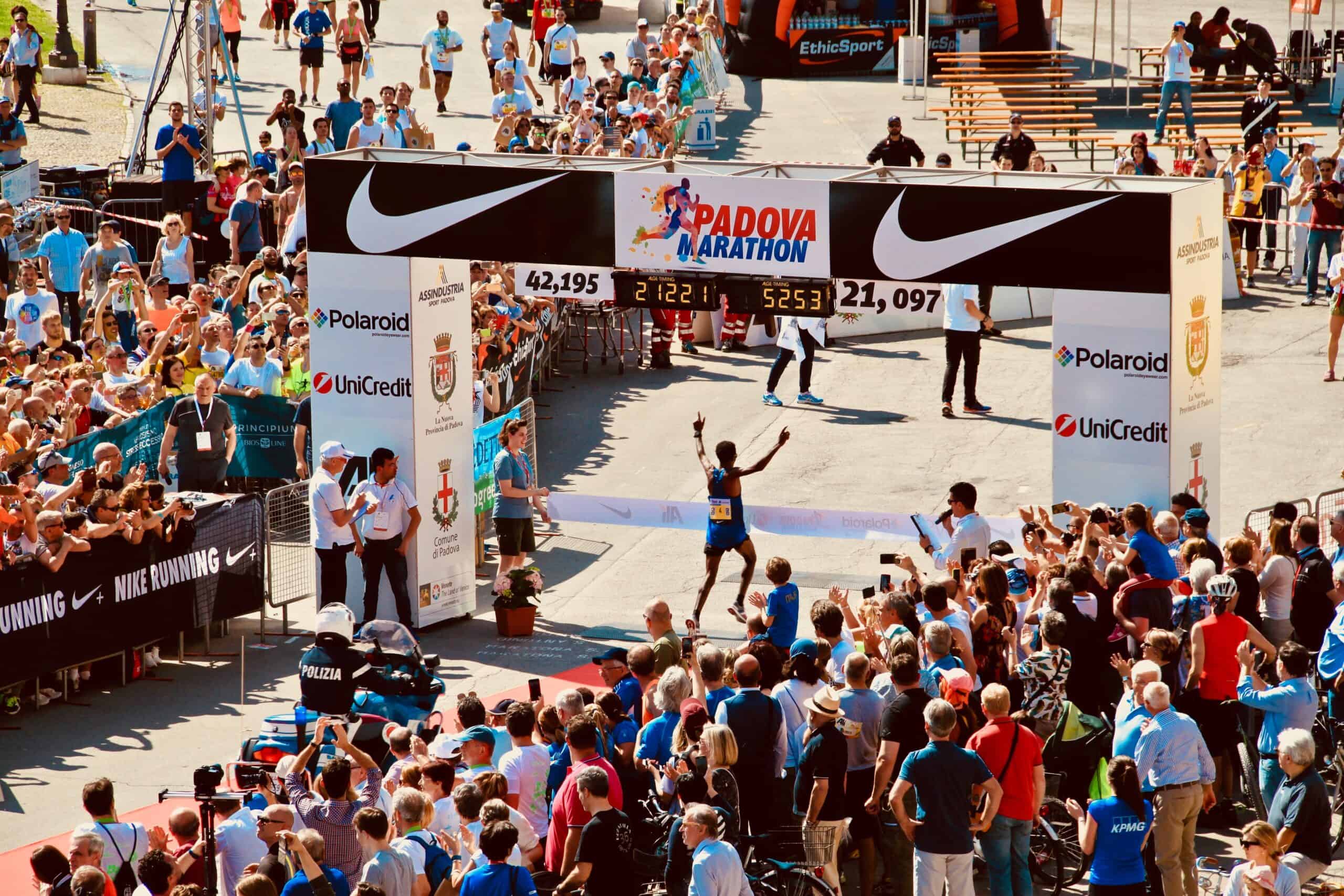 A runner finishing at the Padova Marathon with his hands in the air to screaming crowds. The runner has gone from couch to half marathon.