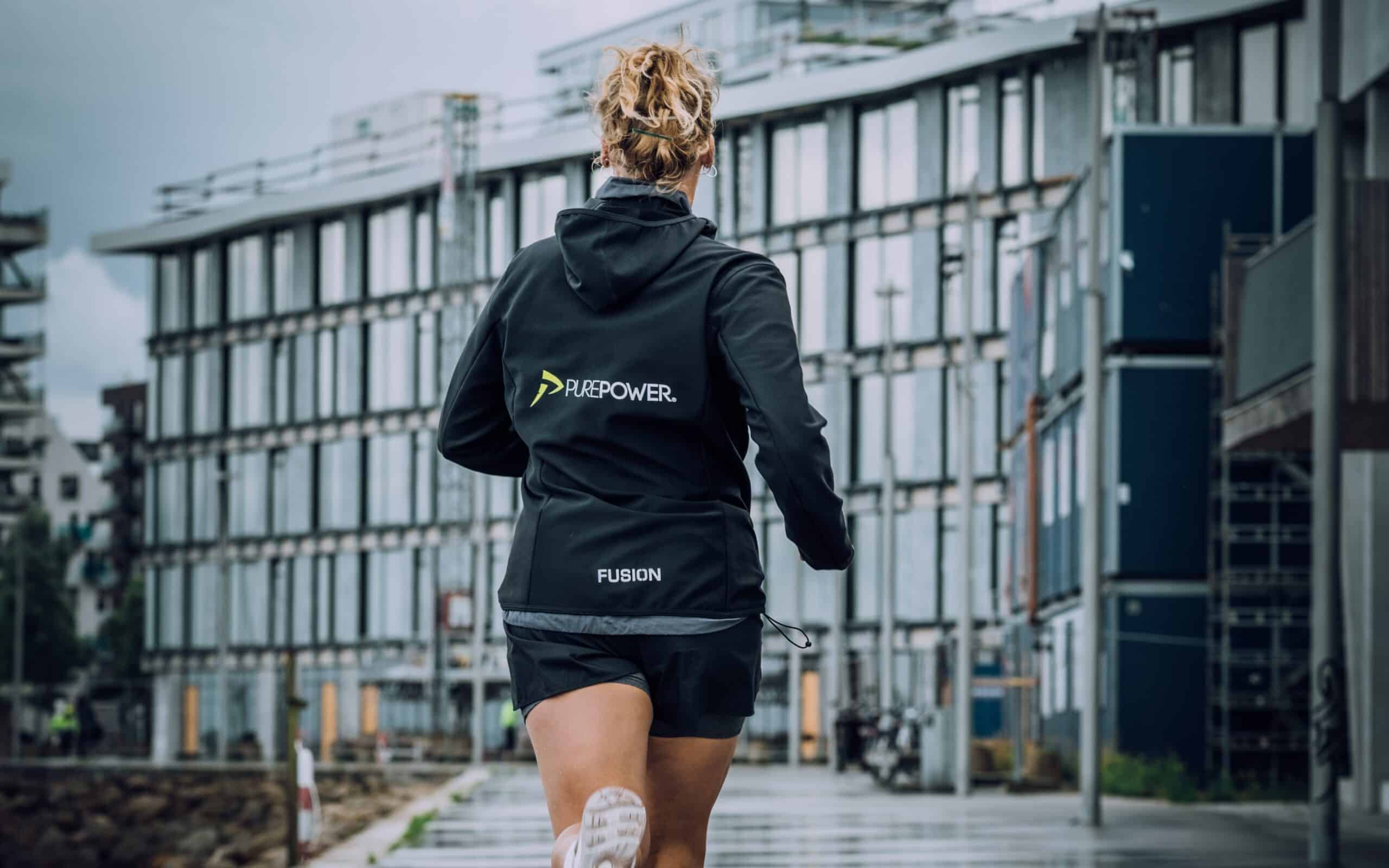 A female runner running in the rain with a Purepower rain jacket.