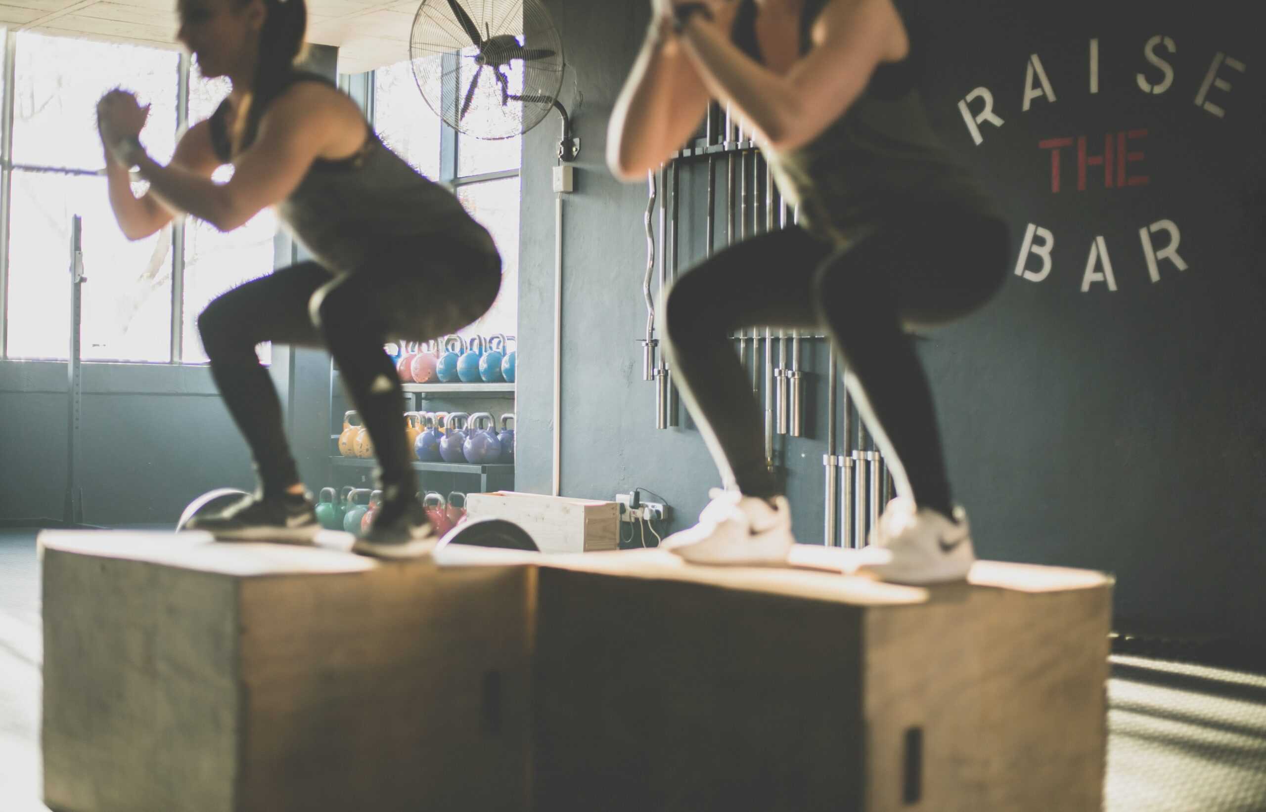 Strength training for runners includes lower body workouts with a jump squat for two women.