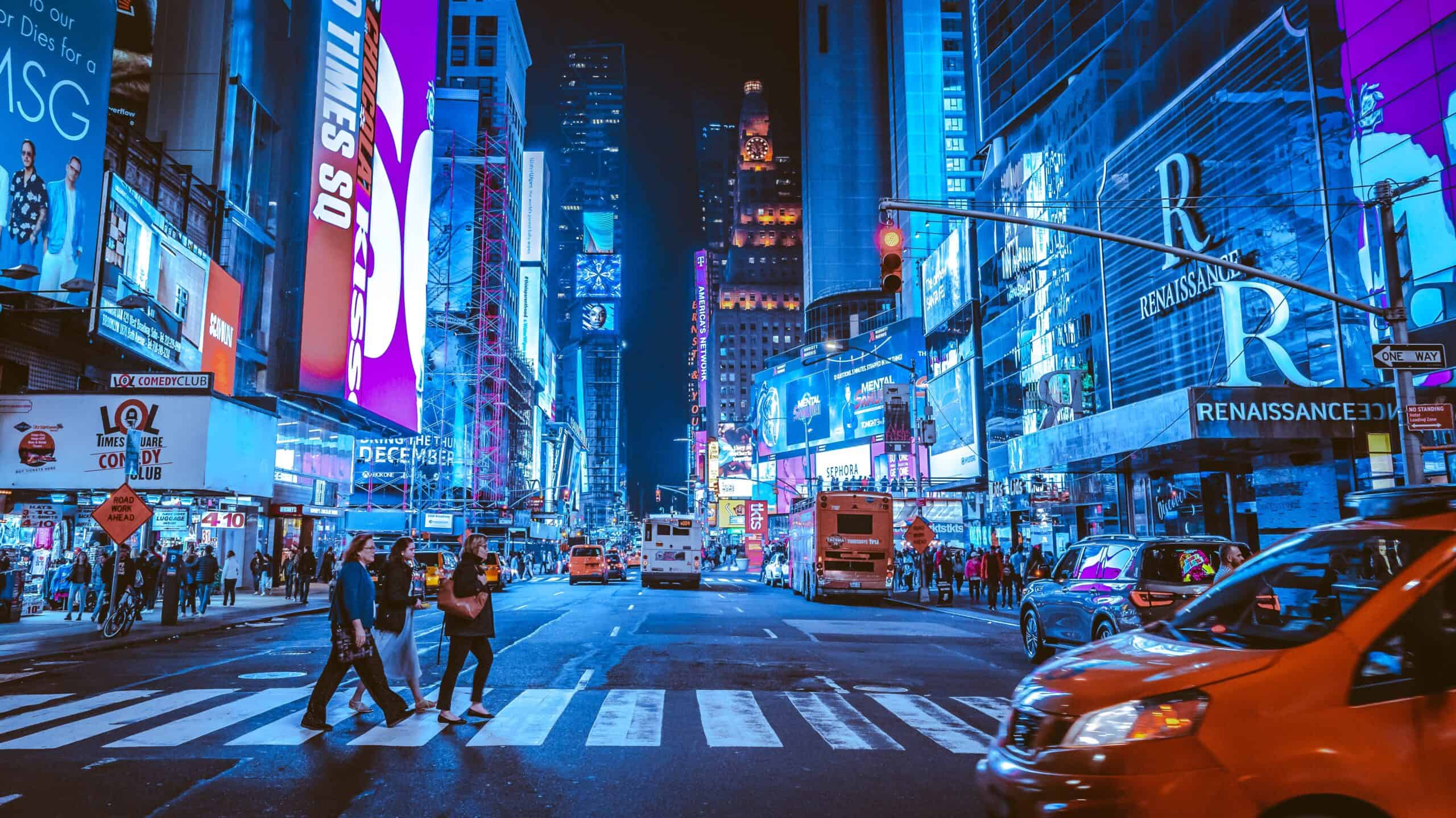 A couple walking through Times Square at night.