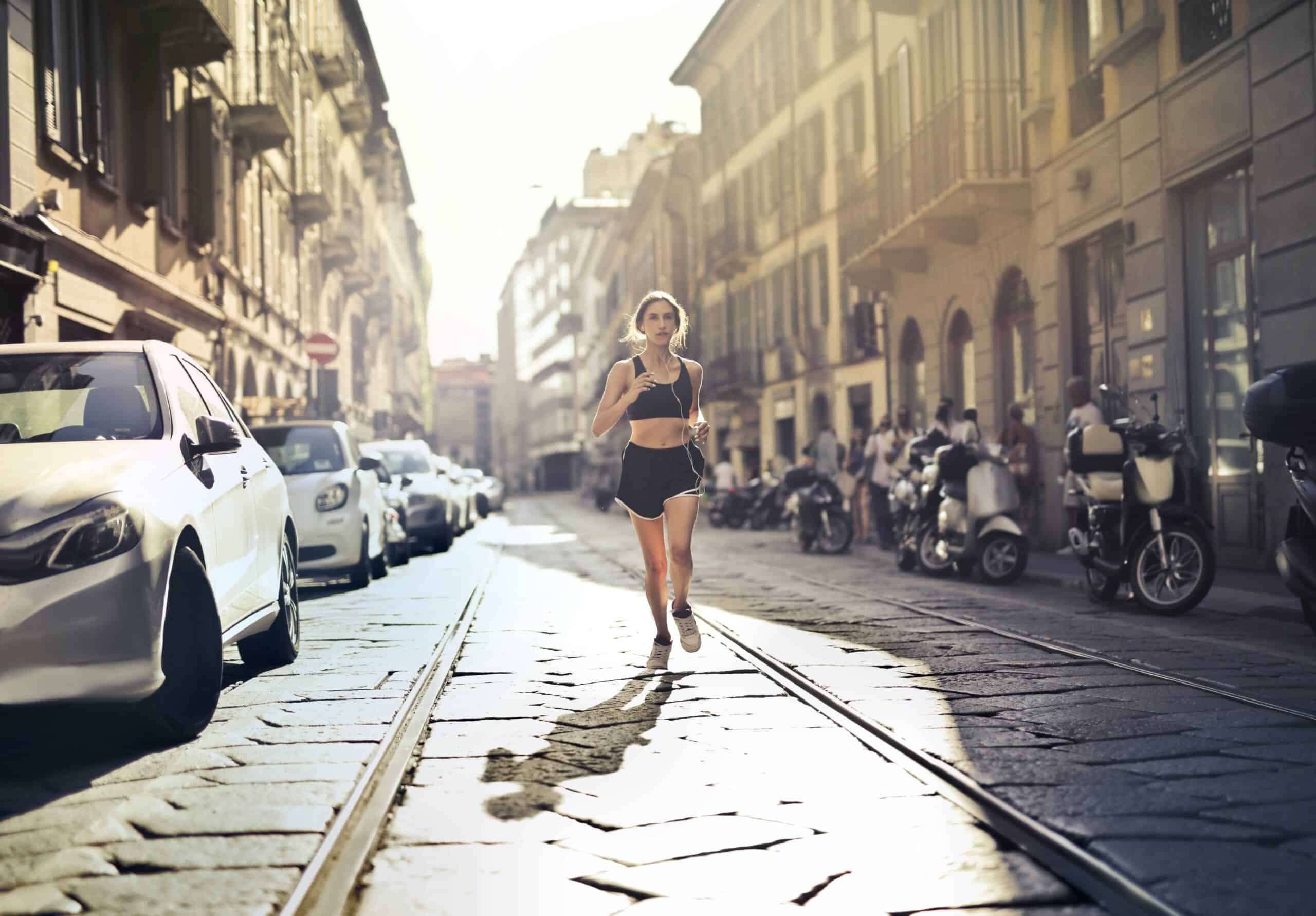 A woman in the middle of a European city running down the middle of a street.