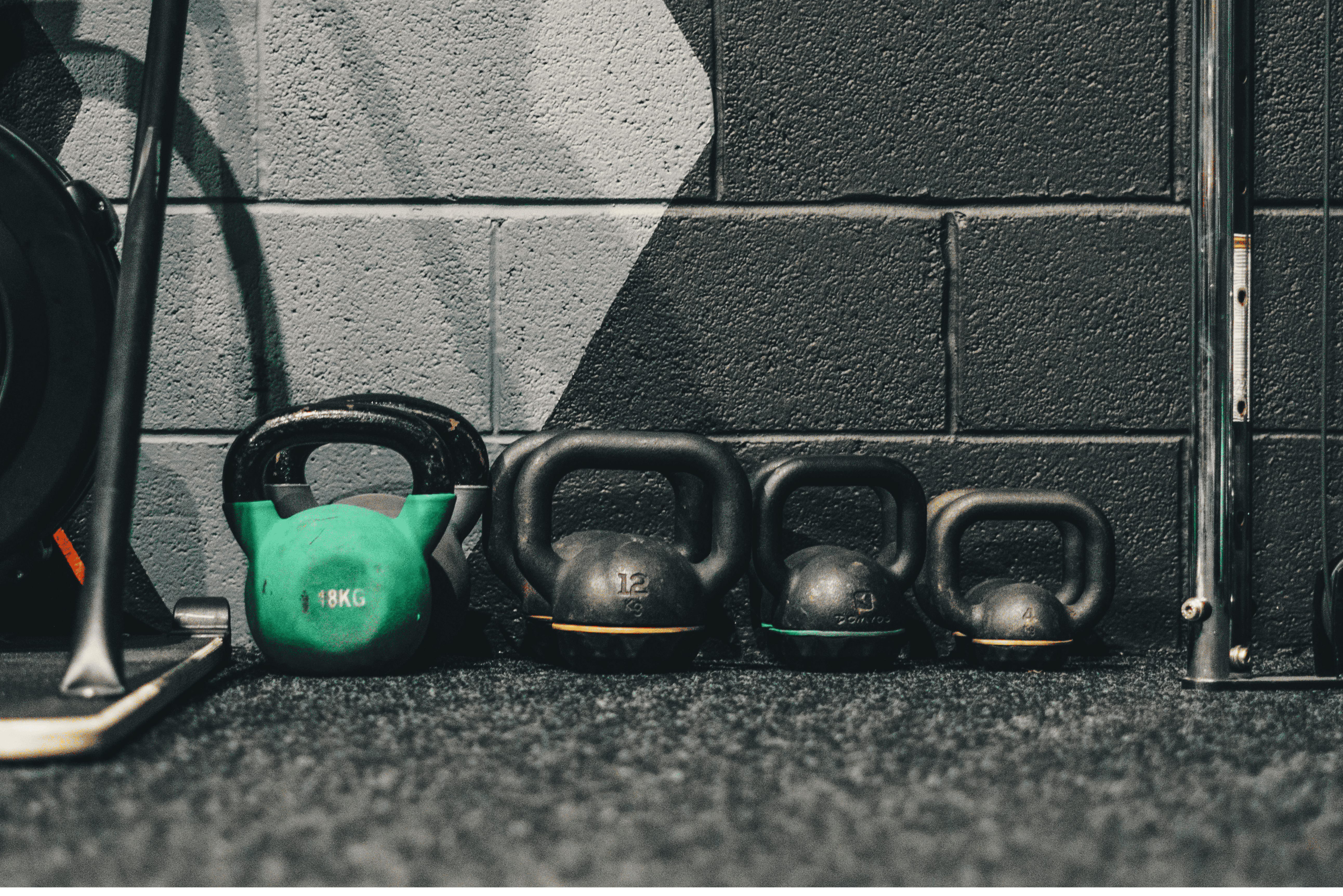 different sizes of kettlebells against a gym wall