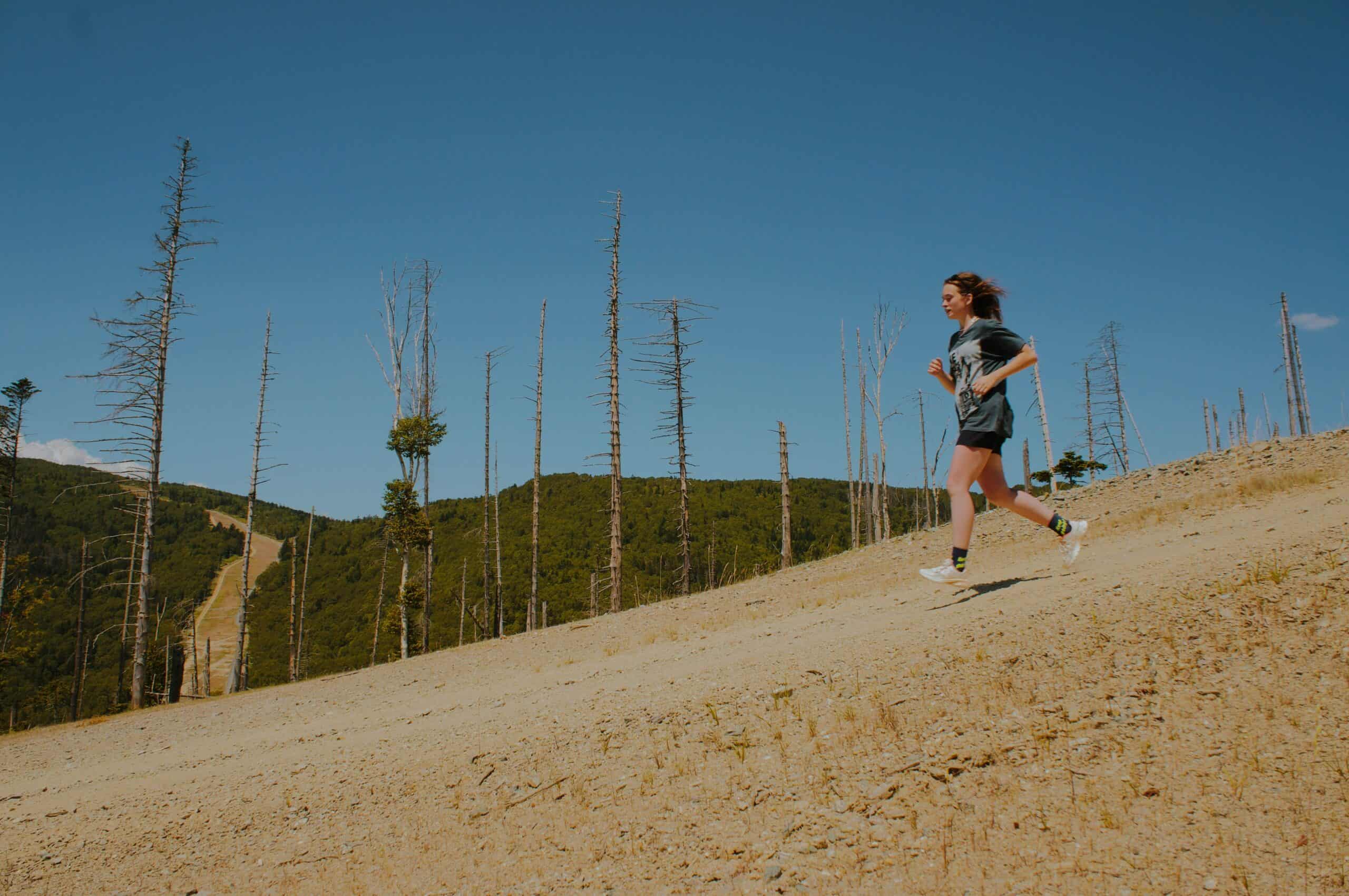 Woman running downhill having to adjust her half marathon pacing strategy because of the decline. 