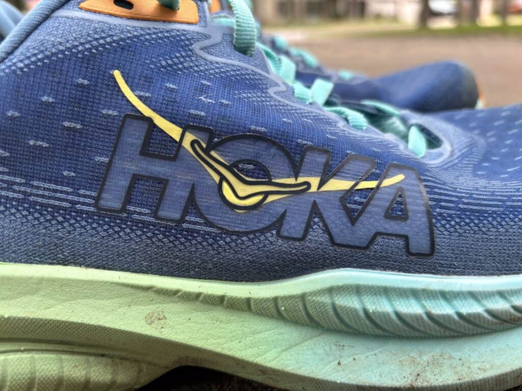 Close-up of the Hoka logo on a pair of well-worn Hoka Mach 6s.