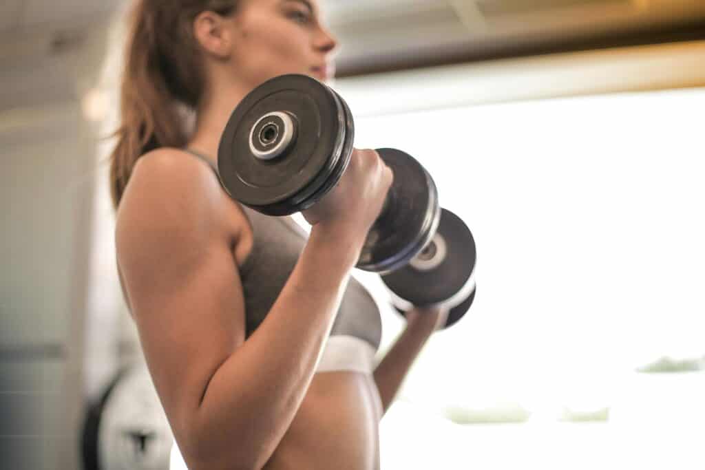 Woman holding dumbells, strength training in the gym