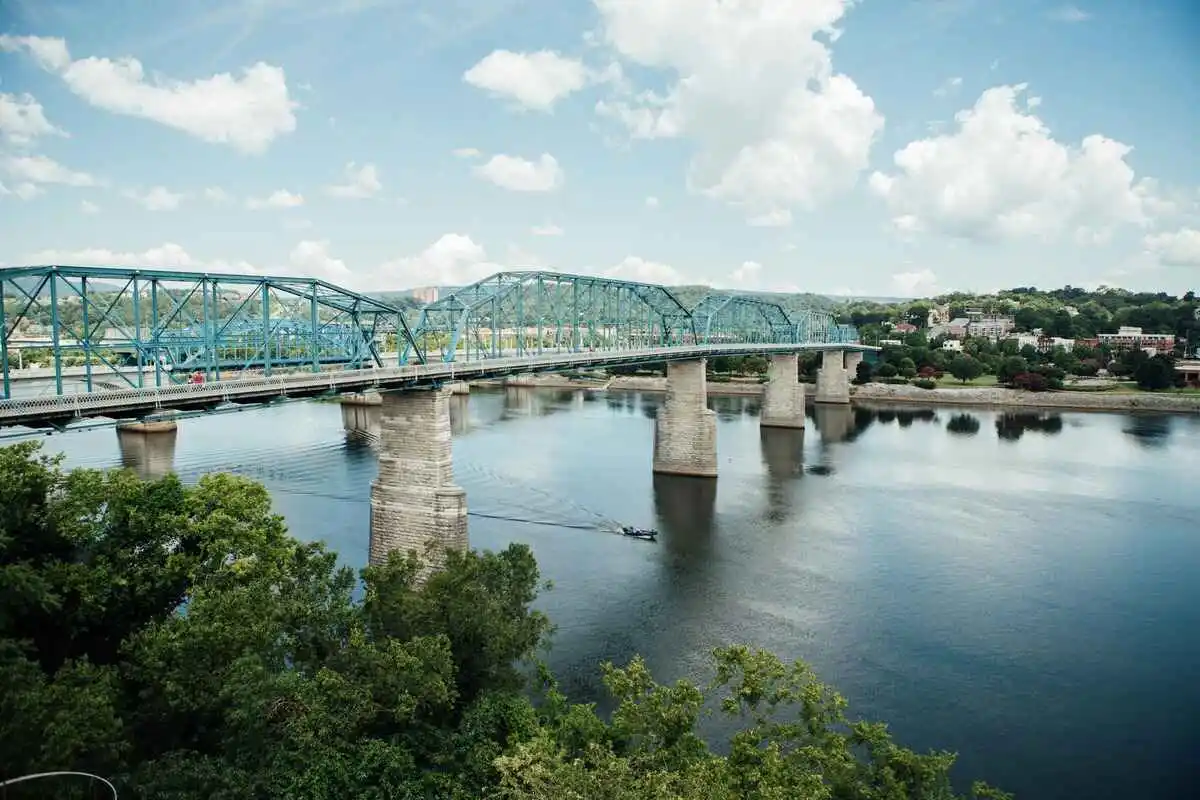 a bridge over water with trees and a boat in Chattanooga home to the 7 Bridges Marathon