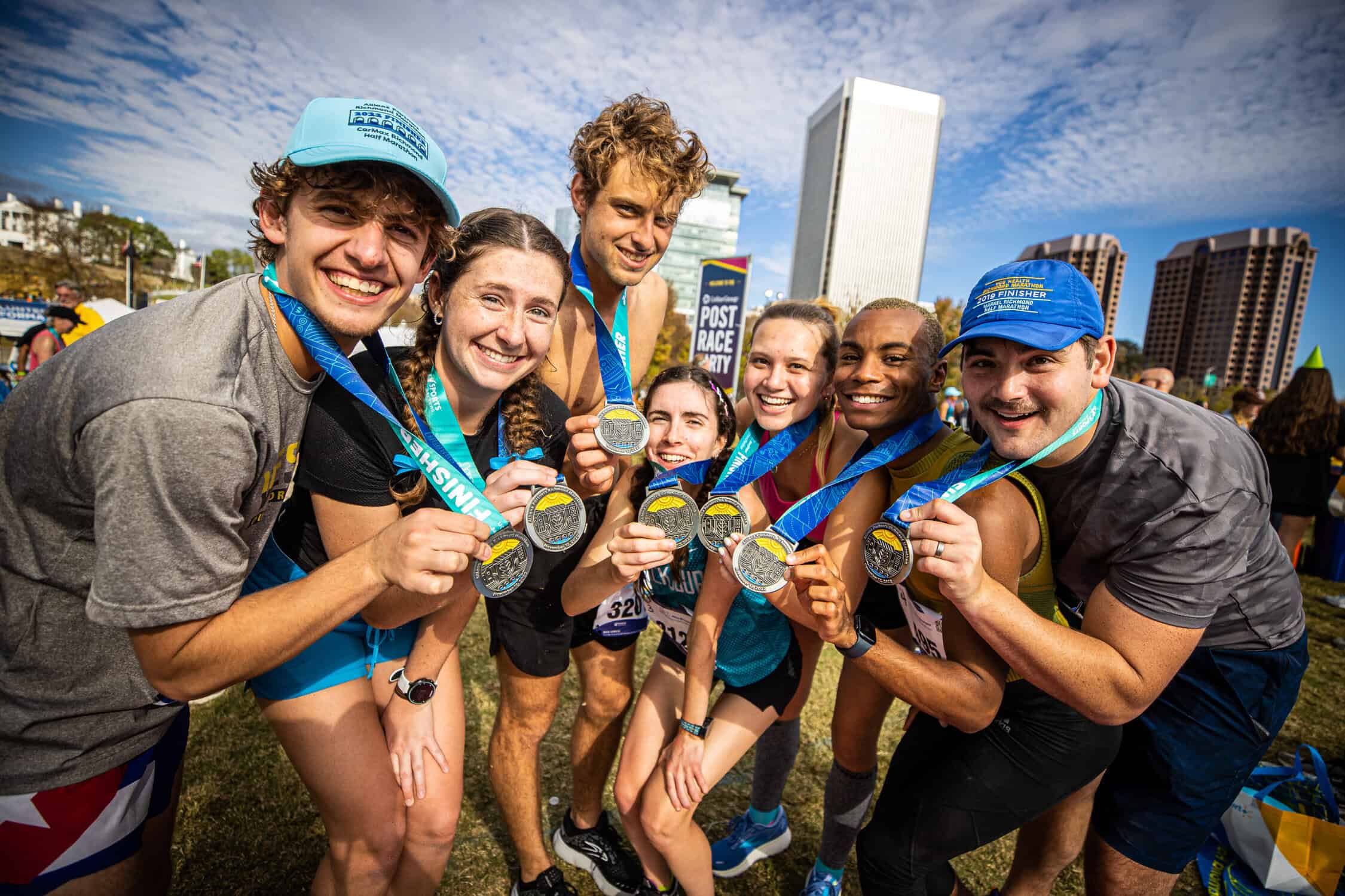 A group of people holding their race medals, smiling, after finishing the Richmond Marathon