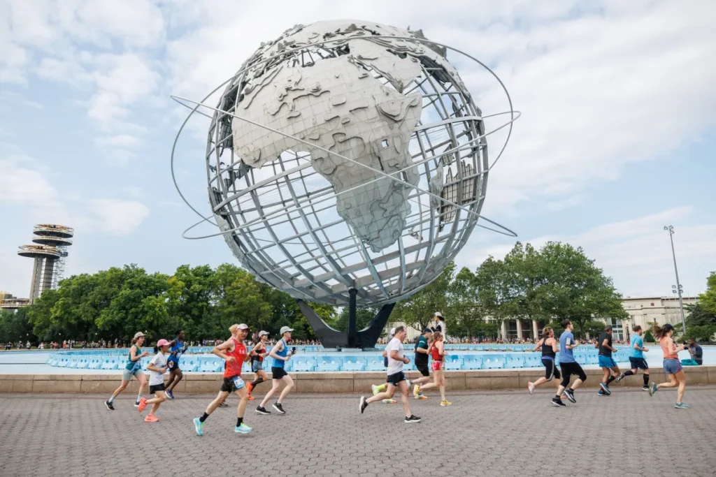 runners passing the world statue in queens during the Citizens Queens 10K race 