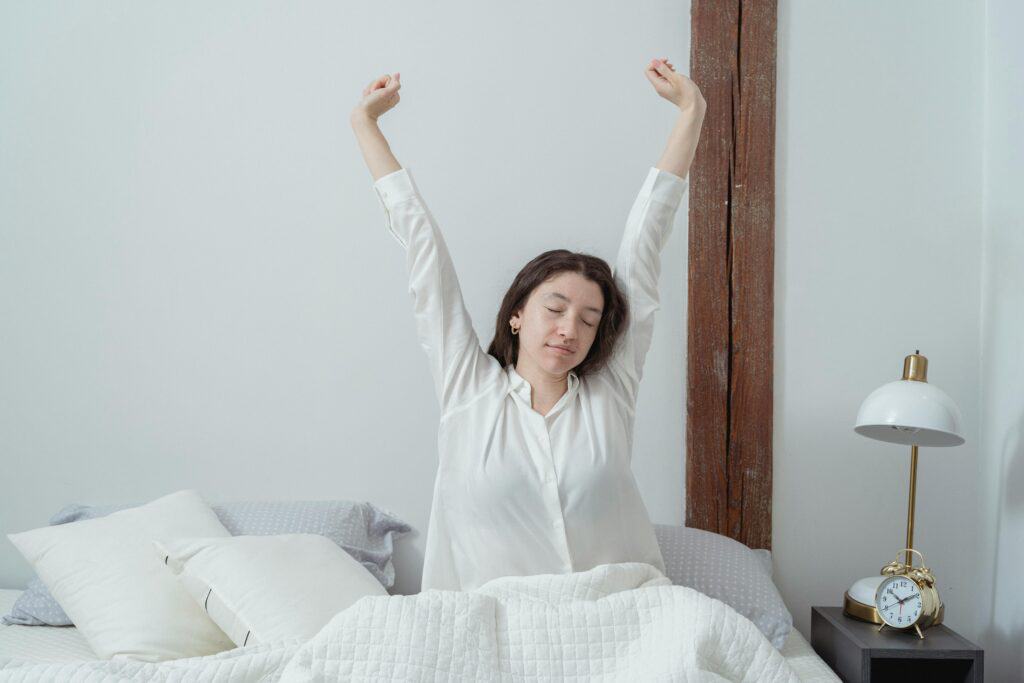 Girl stretching overhead in bed after waking up in the morning